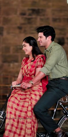 a man riding on the back of a motorcycle next to a woman in a red and yellow dress