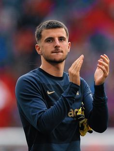 a soccer player is applauding with his hands in the air while wearing a blue shirt