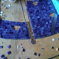 the floor is being worked on with blue glass mosaic tiles and wood planks around it