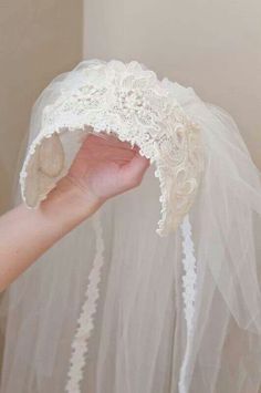 a person holding up a veil on top of a white piece of cloth in their hand