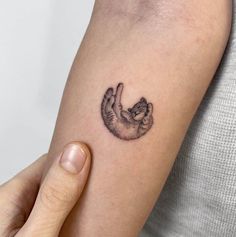 a small cat tattoo on the left arm and wrist is shown in black ink,