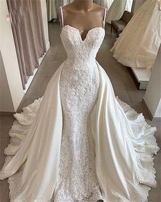 a wedding dress on display in front of a mirror with other gowns behind it