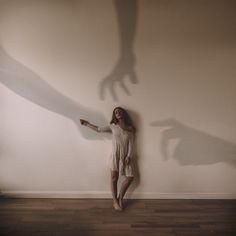 a woman standing in front of a wall with her shadow on the wall