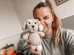 a woman is holding a stuffed dog in her right hand and smiling at the camera