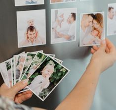 a person holding up several photos in front of a wall with multiple pictures on it