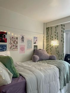 a bed with white sheets and pillows in a bedroom next to a wall with pictures on it