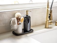 a bathroom sink with soap dispenser, brush and sponge in it