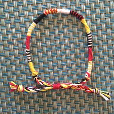 a multi colored necklace is displayed on a woven surface