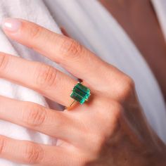 a woman's hand with a green ring on it