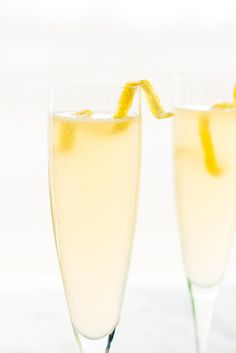 two glasses filled with champagne sitting next to each other on top of a white table