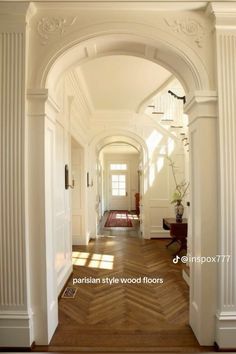 an archway leading into a hallway with wood floors and white trim on the walls, along with potted plants