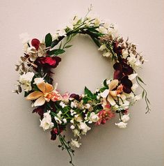 a floral wreath hanging on the wall with white and red flowers in it's center