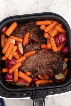 a roaster with carrots, potatoes and meat in it