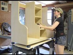 a woman standing in front of a shelf that is made out of plywood planks