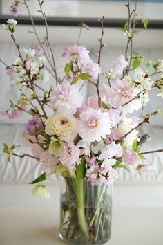 a vase filled with pink and white flowers on top of a table next to a couch