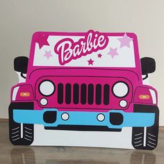 a pink and blue jeep with barbie written on the front is sitting on a table