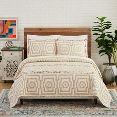 a bed in a room with white brick walls and wooden headboard, potted plants on either side