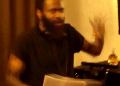 a man with headphones on standing in front of a table and holding his hand out