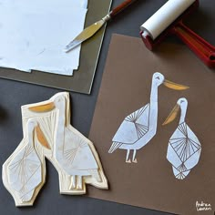 some paper and scissors are laying on the table next to two stork cut outs