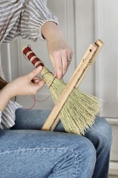 a woman sitting on a chair holding a broom