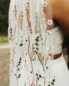 the back of a woman's dress with flowers and vines on it, in front of an instagram