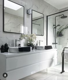 a white bathroom with two sinks and mirrors