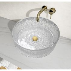 a clear glass sink with gold faucet handles