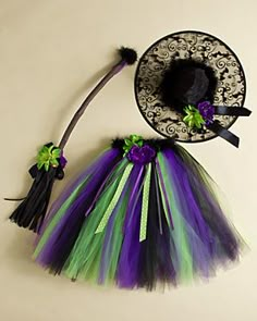 a purple and green tutule skirt next to a black hat on a white background