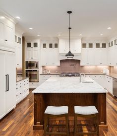 a large kitchen with white cabinets and wooden floors