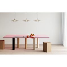 a pink table with two stools and a bowl of fruit on it in front of a white wall