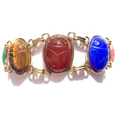 Looking for colorful jewelry? A go with everything good luck bracelet? This vintage scarab bracelet has seven gorgeous semi precious stones, set in 12K gold filled open bezels with double links in between. Gemstone scarabs are are a very nice size. This eye catching gold filled bracelet stands out all on its own! Era: Mid Century. Bracelet is 7.25 inches long by 0.8 inches wide. Scarabs with their settings are 21.5mm by 16.5mm.  Marks: Hallmark, 1/20 12K G. F., hallmark. Gemstones from spring ri Bracelet Stands, Scarab Bracelet, Cameo Pendant Necklace, Good Luck Bracelet, Equestrian Jewelry, Green Chalcedony, Cameo Pendant, Colorful Jewelry, Blue Chalcedony