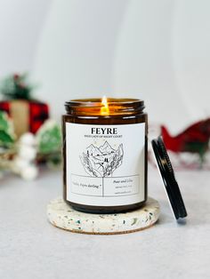 a candle sitting on top of a white table next to a pen and christmas decorations