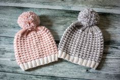 two knitted hats sitting next to each other on top of a wooden floor,