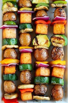 skewered vegetables and meats are arranged in a white dish on the grill