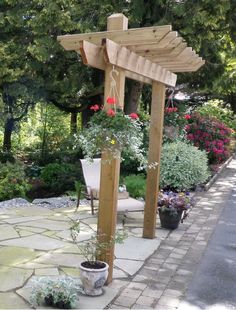 a wooden pergolan with potted plants and flowers on the side of it