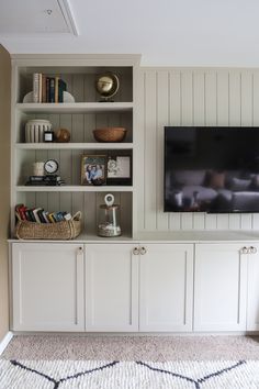 a flat screen tv mounted to the side of a white bookcase in a living room