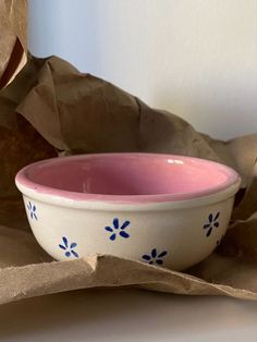 a pink and white bowl sitting on top of a brown paper bag