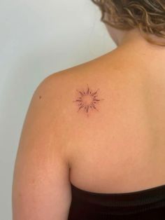 the back of a woman's shoulder with a small sun tattoo on her upper arm