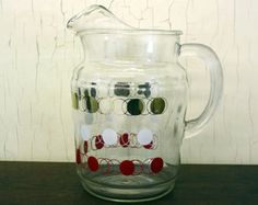 a glass pitcher sitting on top of a wooden table next to a white painted wall