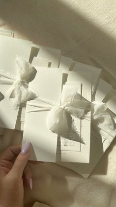 a person is holding some cards with bows on them and the paper has been folded