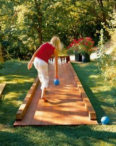 an image of a person playing with balls on a wooden walkway in the grass and trees