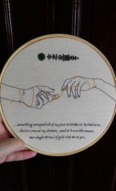 someone holding up a cross stitched artwork with the creation of hands touching each other