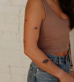 a woman with a tattoo on her left arm and right arm behind her is wearing jeans