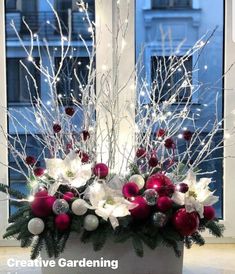 a planter filled with white and red christmas ornaments in front of a large window