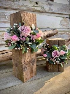 two wooden vases with flowers are sitting on the ground next to some wood logs