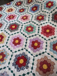 a quilt with many flowers on it is laying on the floor next to a chair