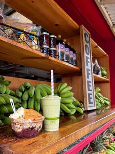 there are many green bananas on the shelves in this store, and one is holding a smoothie