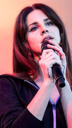 a woman holding a microphone in her right hand and looking up at the sky with an intense look on her face