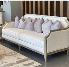 a white couch sitting on top of a tiled floor next to a wooden headboard