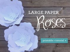 two paper flowers on top of a wooden table with the words large paper roses above them